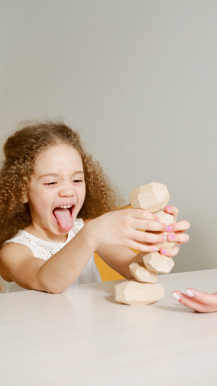 services-04 A happy child with curly hair plays with wooden blocks, enjoying a fun game.